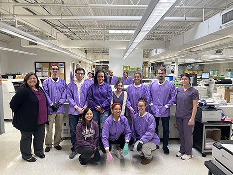 Dominion Diagnostics laboratory staff standing together in the lab wearing purple during Lab Week.